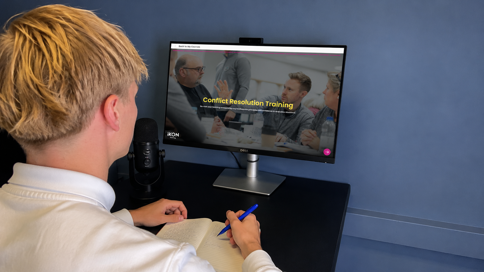 Learner sat at a desk using a computer to use the IKON Academy to complete Conflict Resolution Training