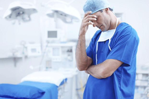 Stressed nurse holding his head from stress at work.