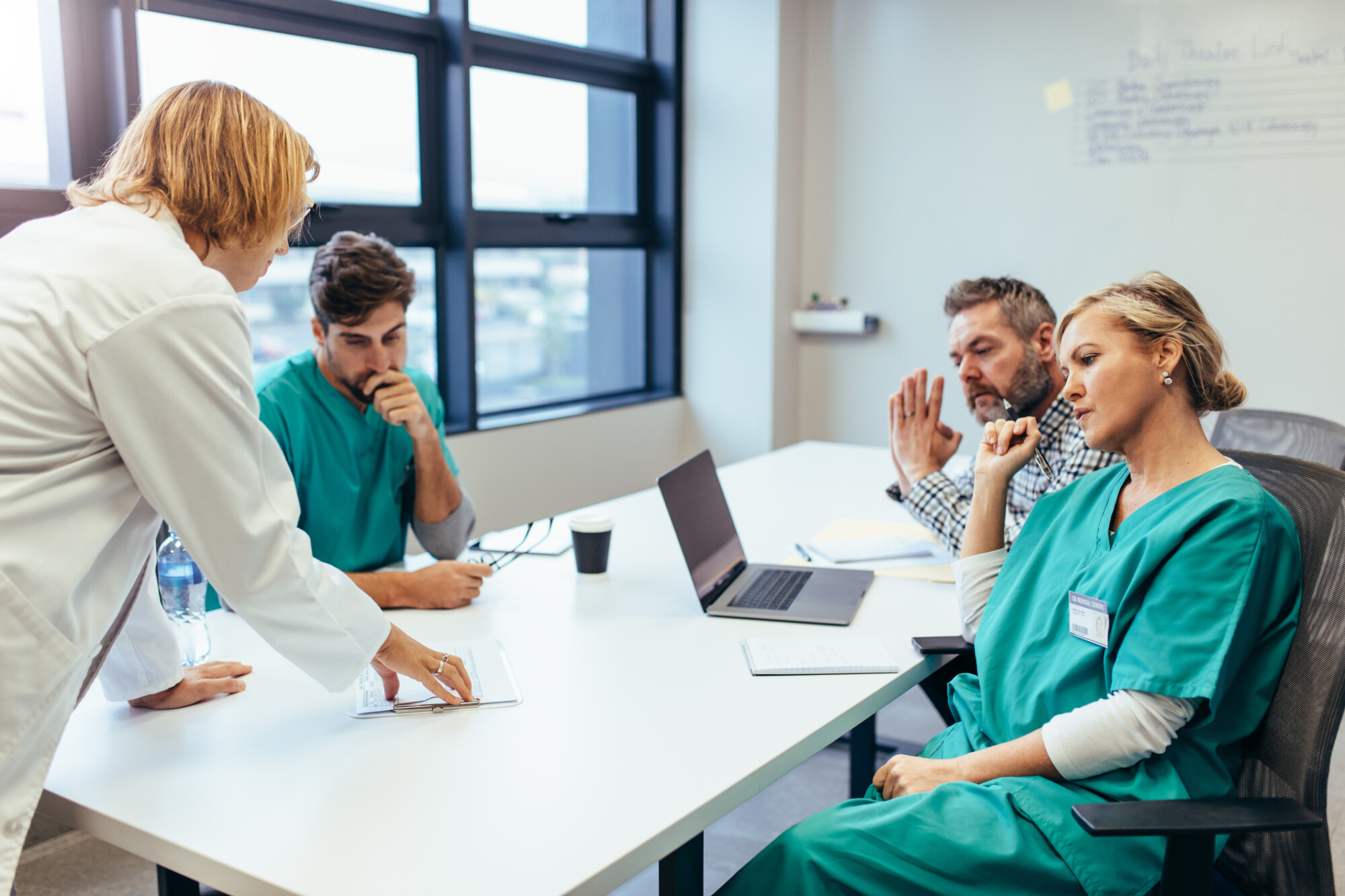Group of medical professionals round a table reporting