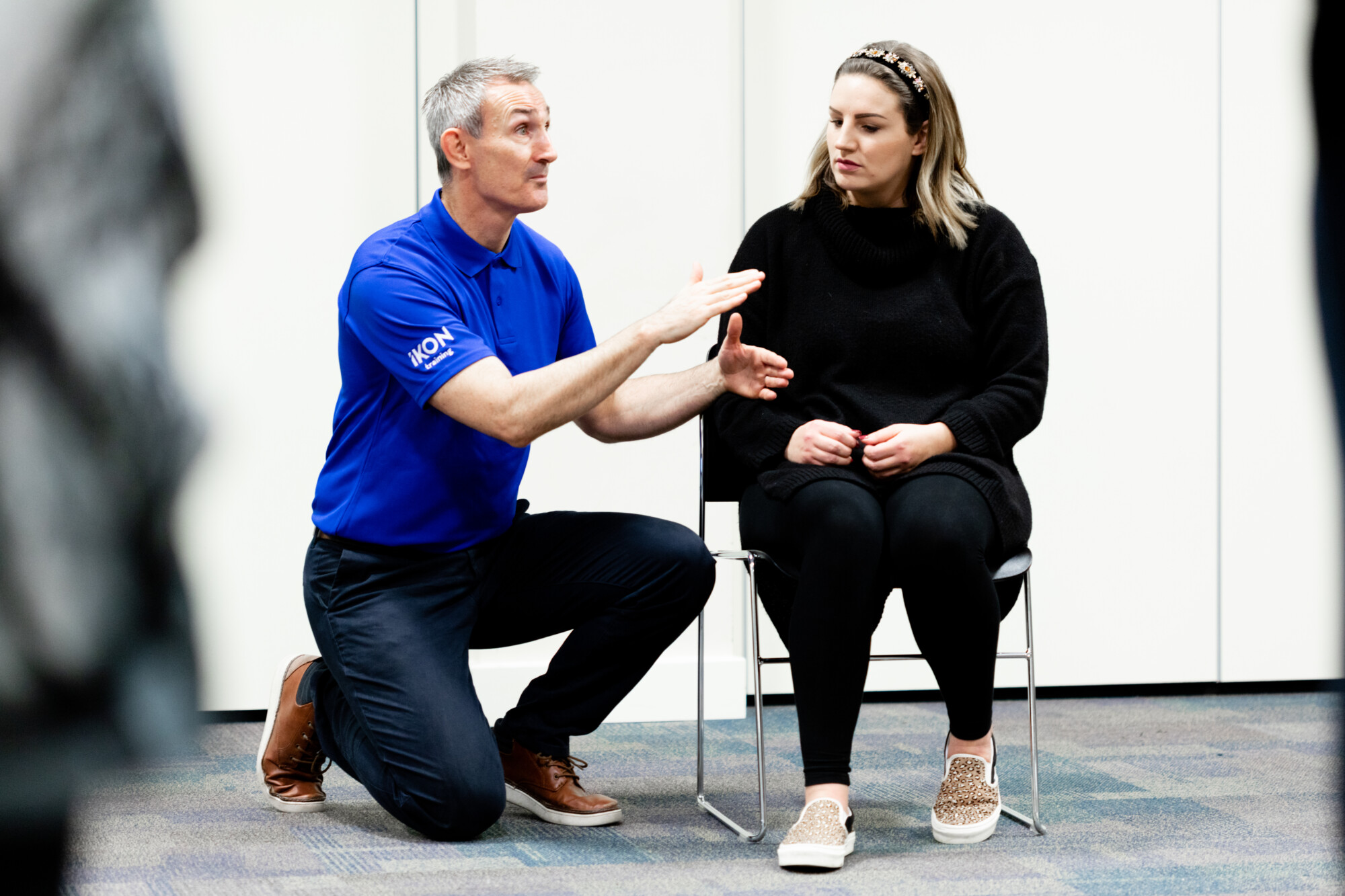 Training Director of IKON Training, James Crown, crouching down to engage with a learner.