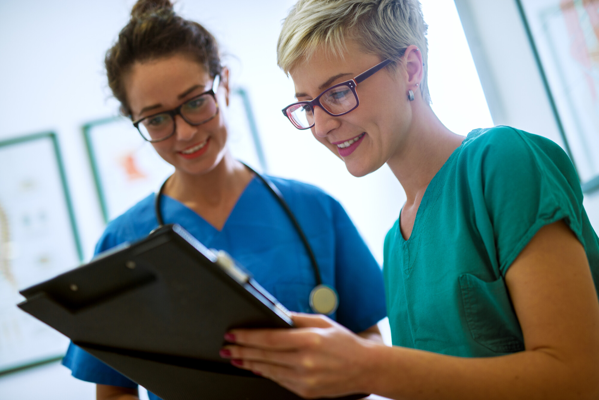 Close up view of two professional NHS nurses with eyeglasses checking the patient papers in a doctors office.