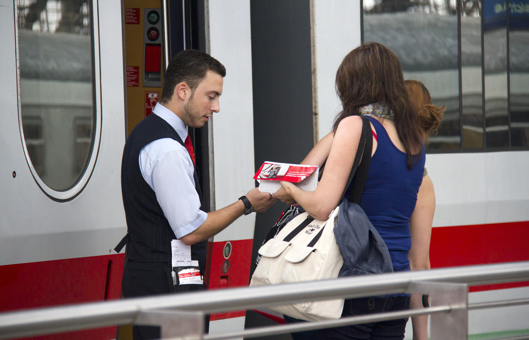 Train conductor checks the tickets of female travelers on an international train in the railway station